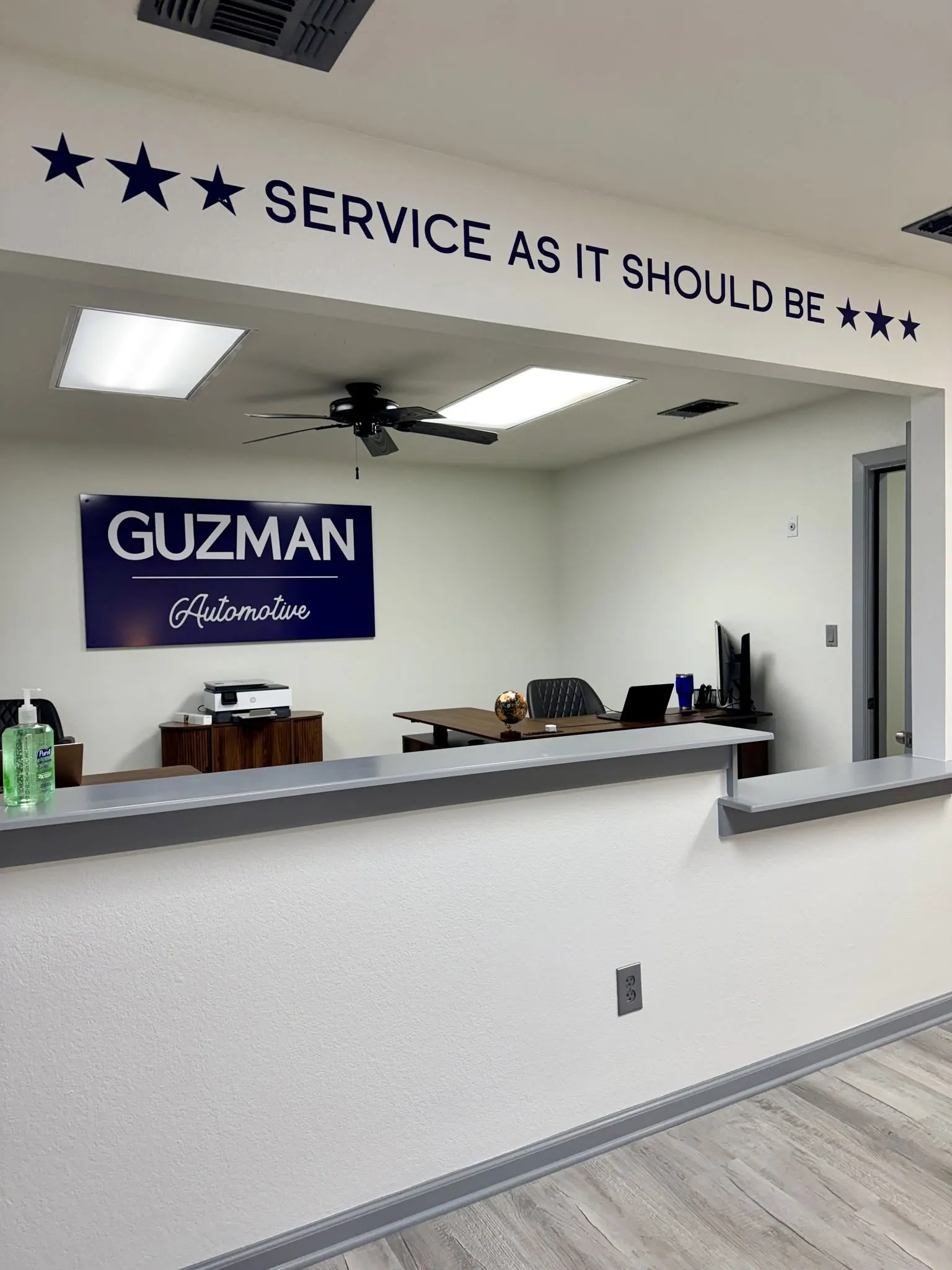 The front desk at Guzman Automotive in Hutto, TX, under a wall reading Service As It Should Be