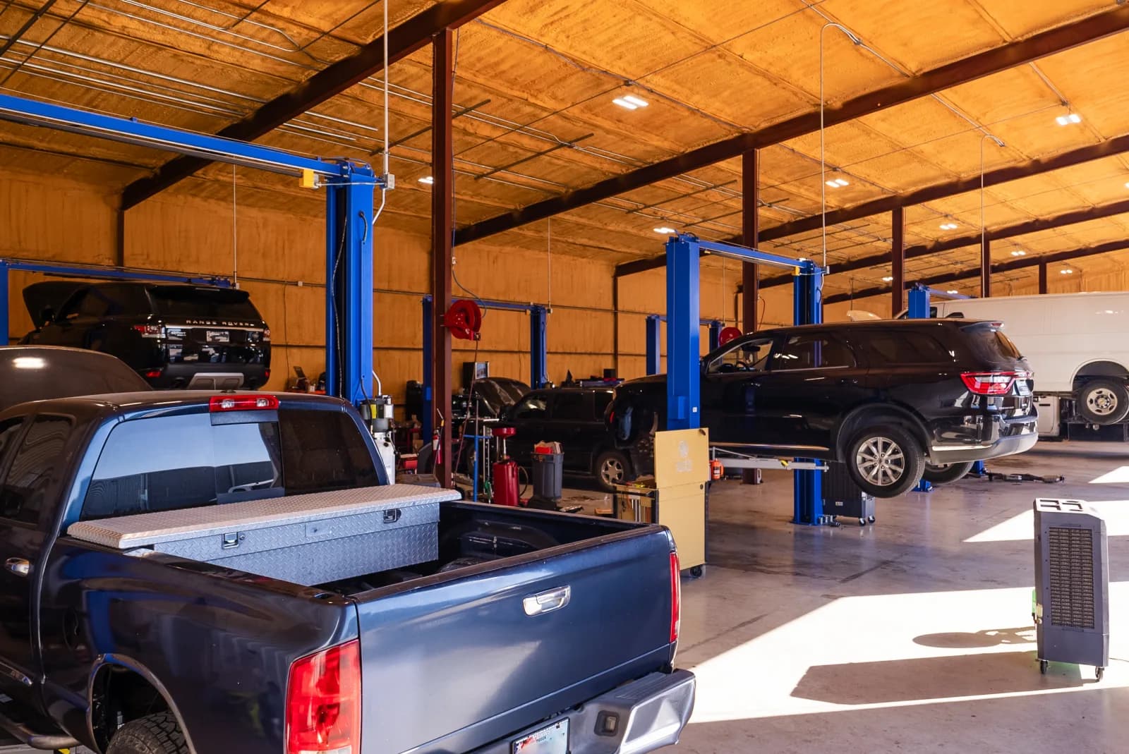 Multiple fleet vehicles on lifts in the Guzman Automotive shop
